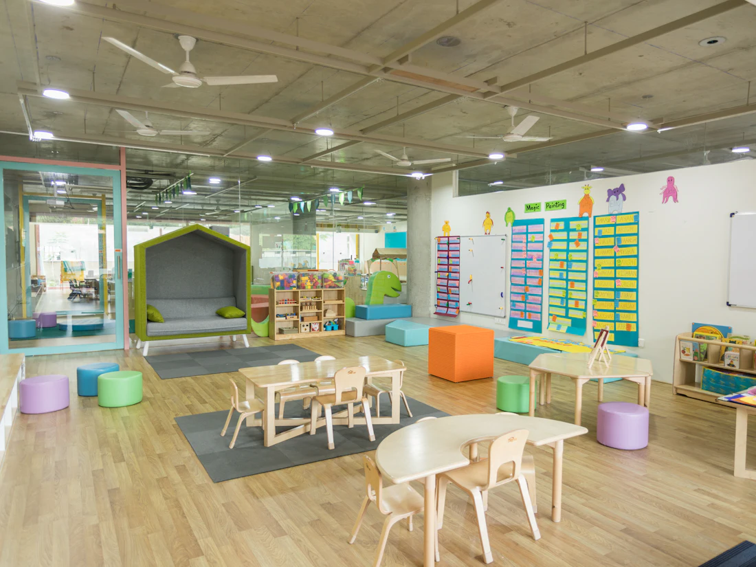 A bright, tidy classroom with small tables and learning centers